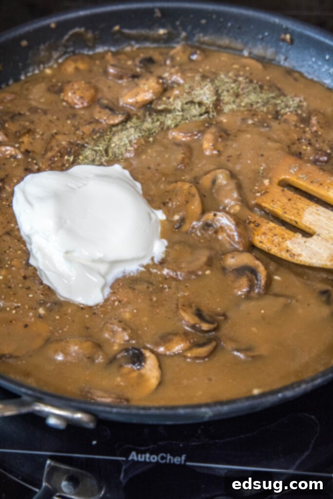 Easy and comforting mushroom stroganoff is loaded with a creamy garlic sauce full of hearty mushrooms, and served over buttery noodles. Mushroom stroganoff in a large skillet with a dollop of sour cream being stirred in with a wooden spoon.