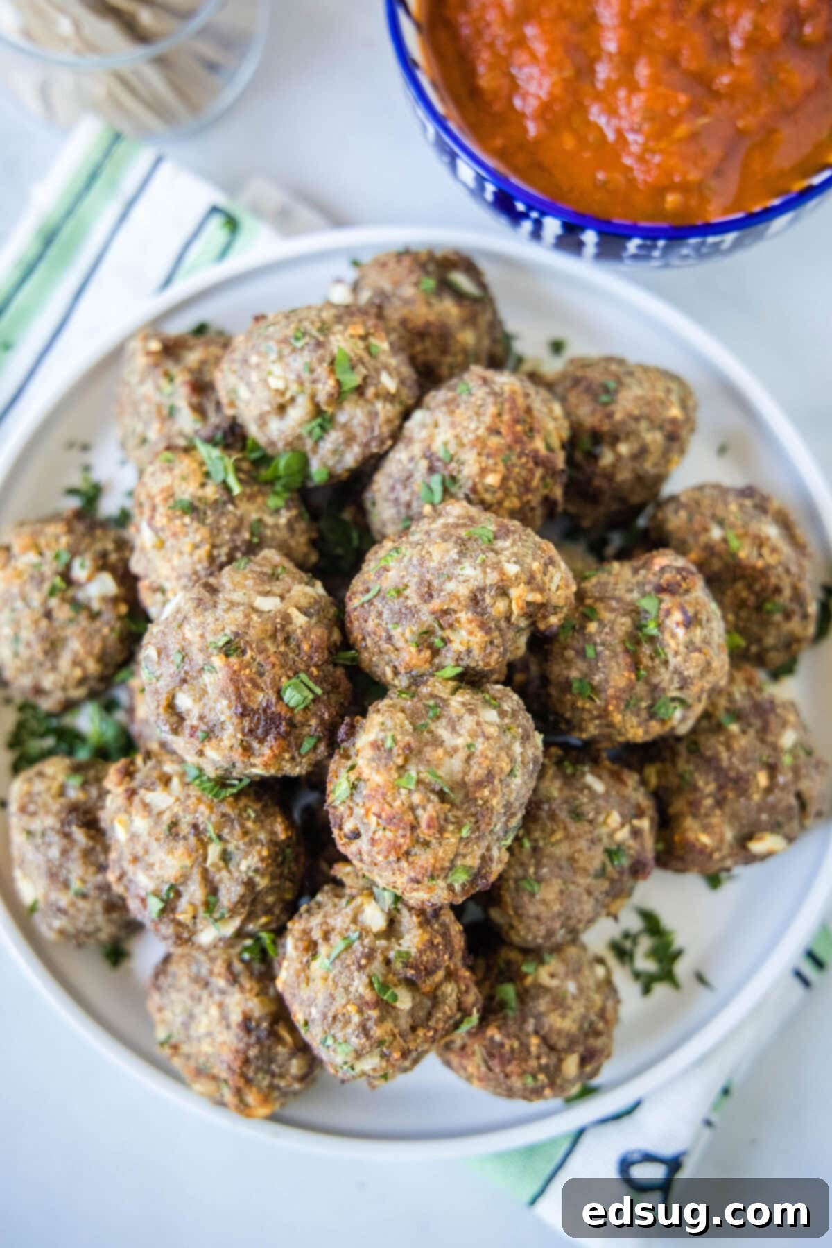 Overhead view of a plate of meatballs next to a bowl of marinara sauce