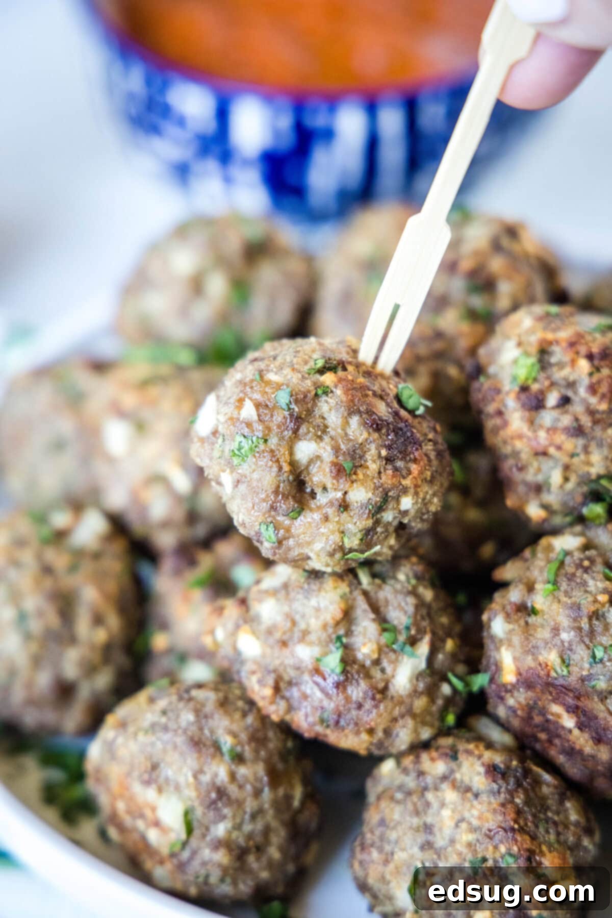 Close up of a plate of meatballs, with one on a skewer