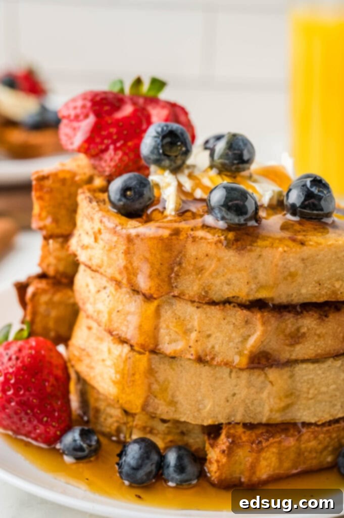 Golden Air Fryer French Toast 2 A beautifully stacked plate of golden Air Fryer French Toast, drizzled with maple syrup and garnished with fresh blueberries and powdered sugar.