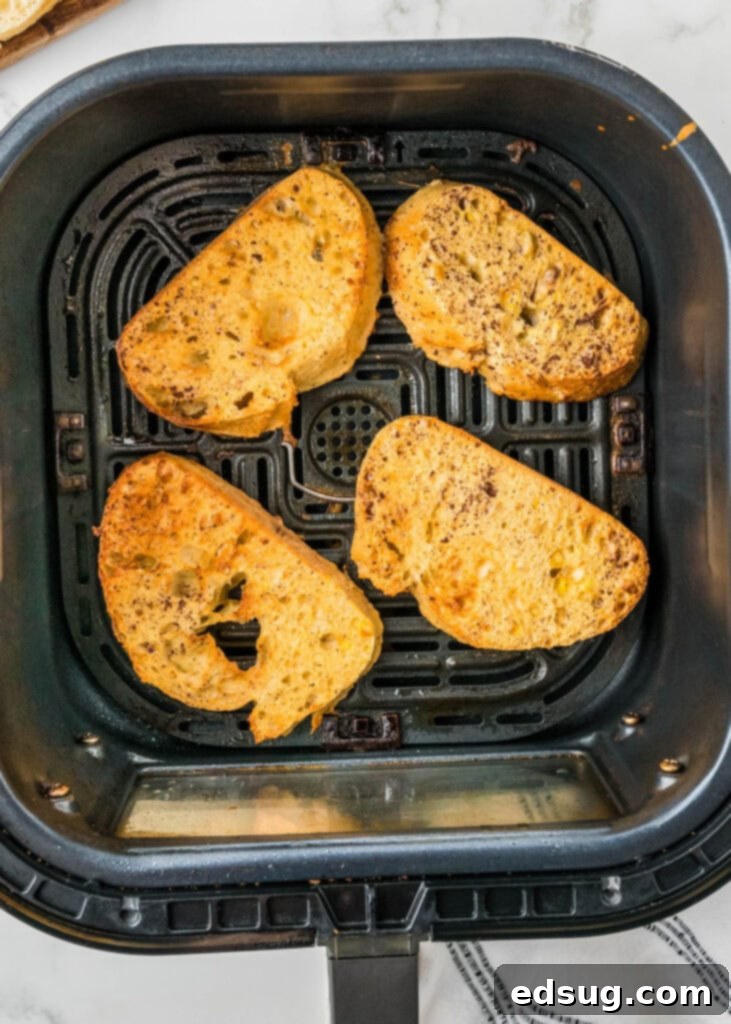 Golden Air Fryer French Toast 4 A single slice of French toast cooking to golden perfection in an air fryer basket, showing its crispy edges.