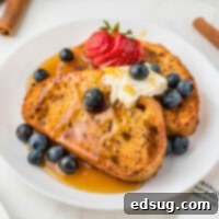 Golden Air Fryer French Toast 8 Cropped close-up of Air Fryer French Toast on a white plate with syrup and berries, showcasing its golden perfection.