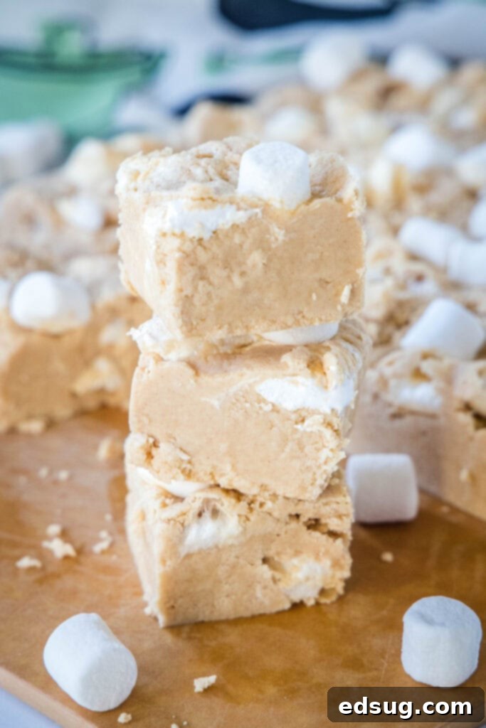 Peanut Butter Marshmallow Fudge 6 Artfully stacked pieces of peanut butter fudge on a wooden cutting board, highlighting their creamy texture.