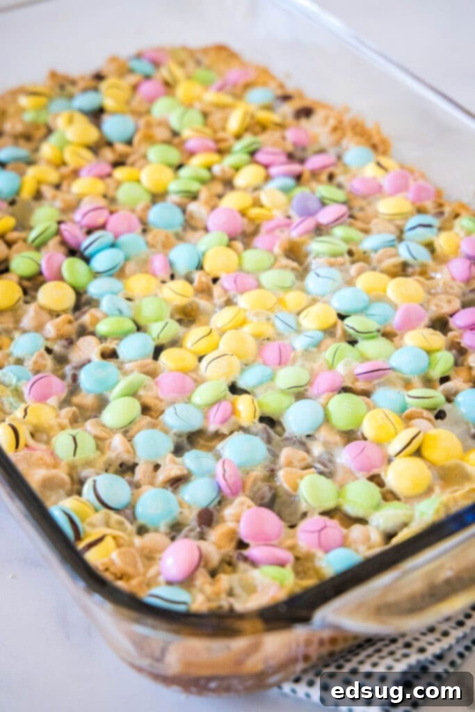 Freshly baked Easter Magic Bars in a 13x9 inch pan, with golden-brown edges and melted, colorful M&M's on top.