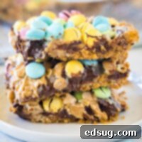A cropped close-up of colorful Easter Magic Bars stacked on a white plate, ready to be served.