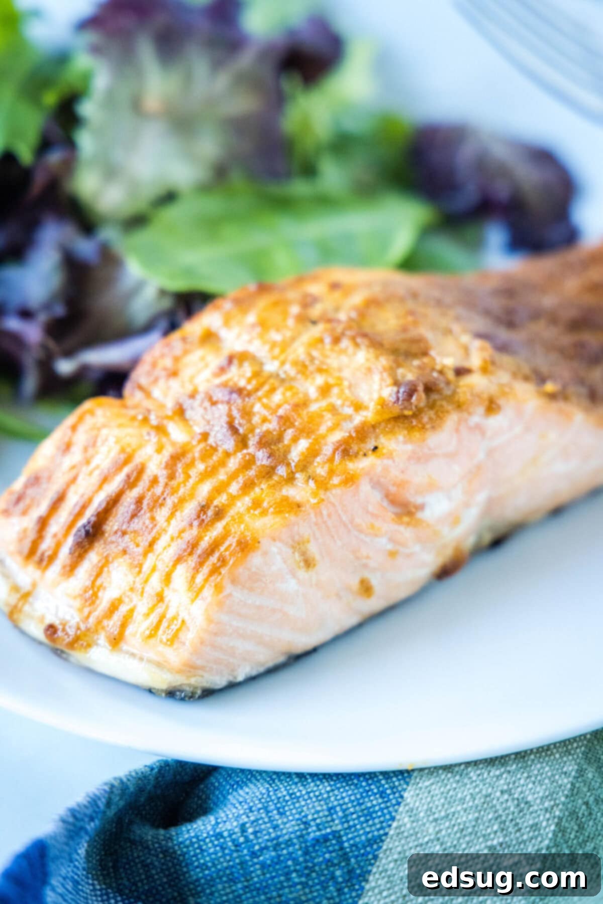 Close up of a salmon fillet on a plate with a salad.