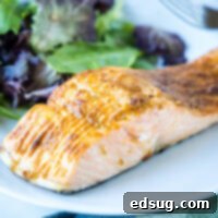 Close up of a salmon fillet on a plate with a salad.