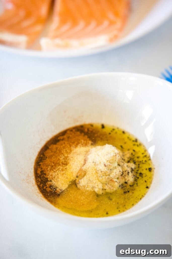 A bowl with oil, mustard, salt, pepper, paprika, and garlic powder, unmixed.