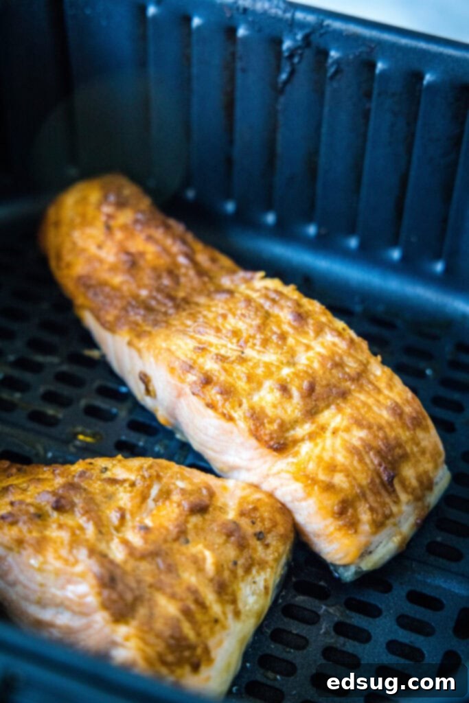 Two cooked salmon fillets in an air fryer basket.