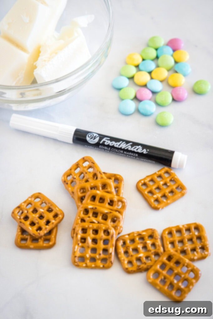 Ingredients for making bunny pretzels laid out: mini pretzels, white almond bark, Easter M&M's, and an edible marker