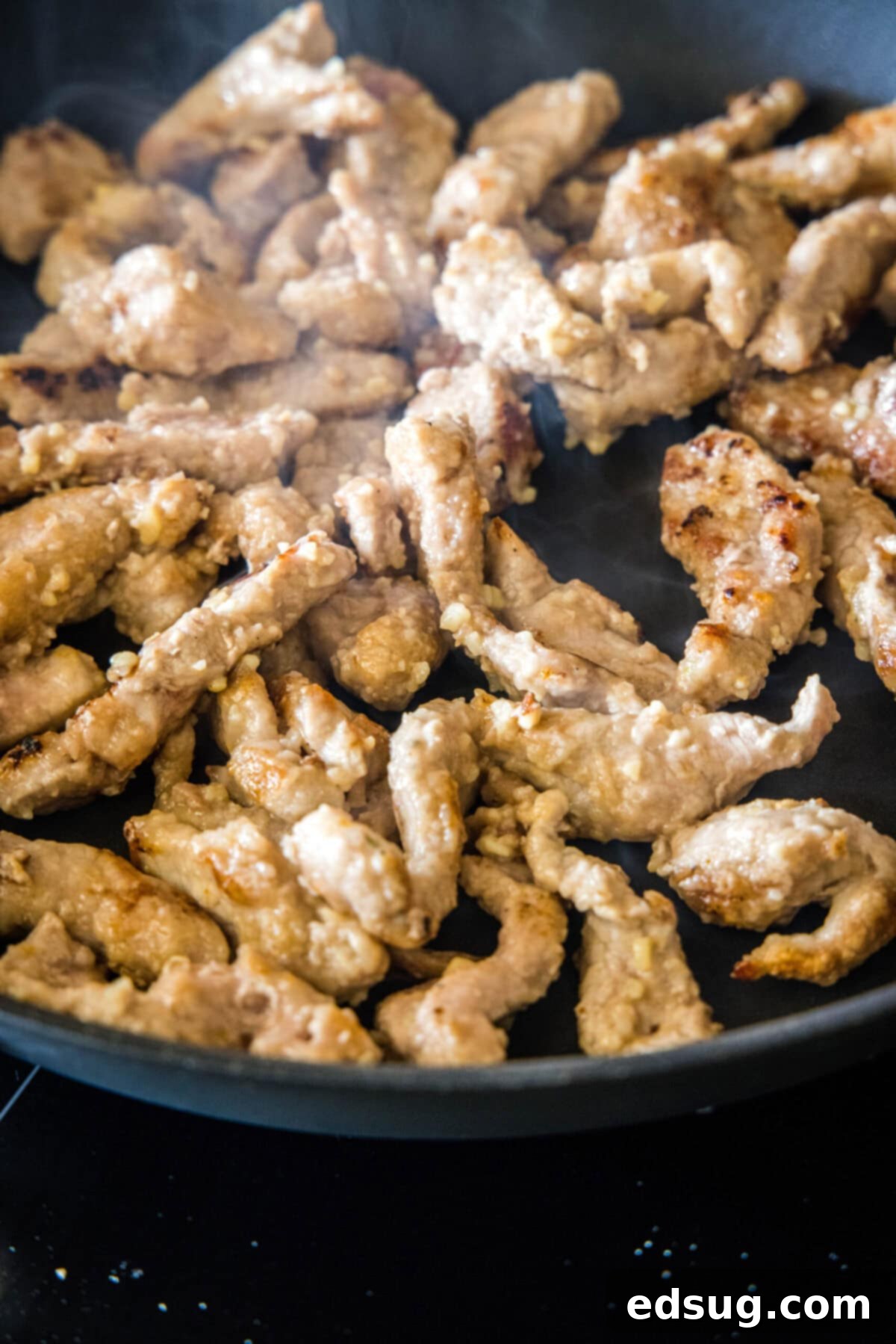 This Mongolian pork is tender, juicy, sweet, sour, a little bit spicy, and so much better than takeout, plus it only takes 20 minutes. Strips of pork searing in a hot skillet.