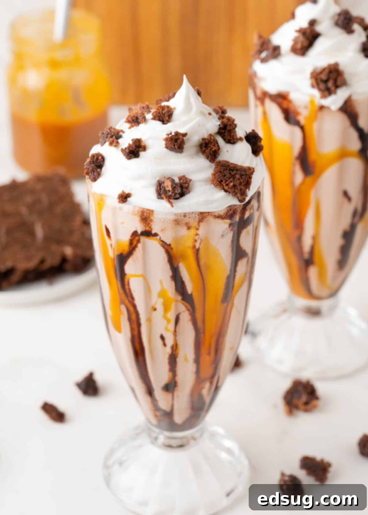 Brownie Bliss Shake 2 brownie milkshakes in glasses topped with whipped cream and brownies