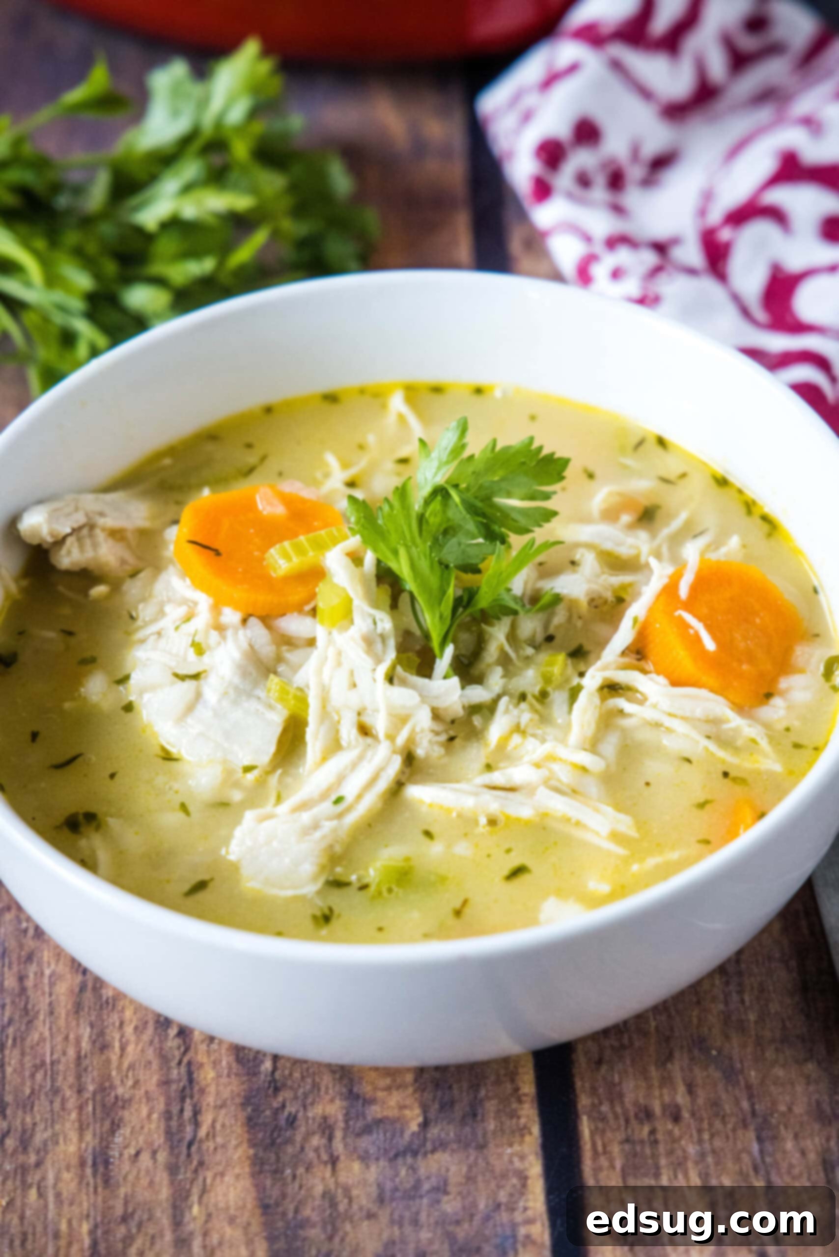 Homemade Chicken Rice Soup: A comforting and easy meal for any occasion. A steaming bowl of homemade chicken rice soup garnished with fresh parsley, served on a rustic wooden table.