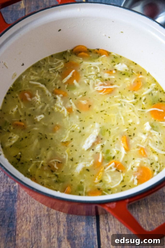 Hearty Chicken Rice Soup, Freshly Cooked. A large pot filled with homemade chicken rice soup, steaming gently, ready to be served.