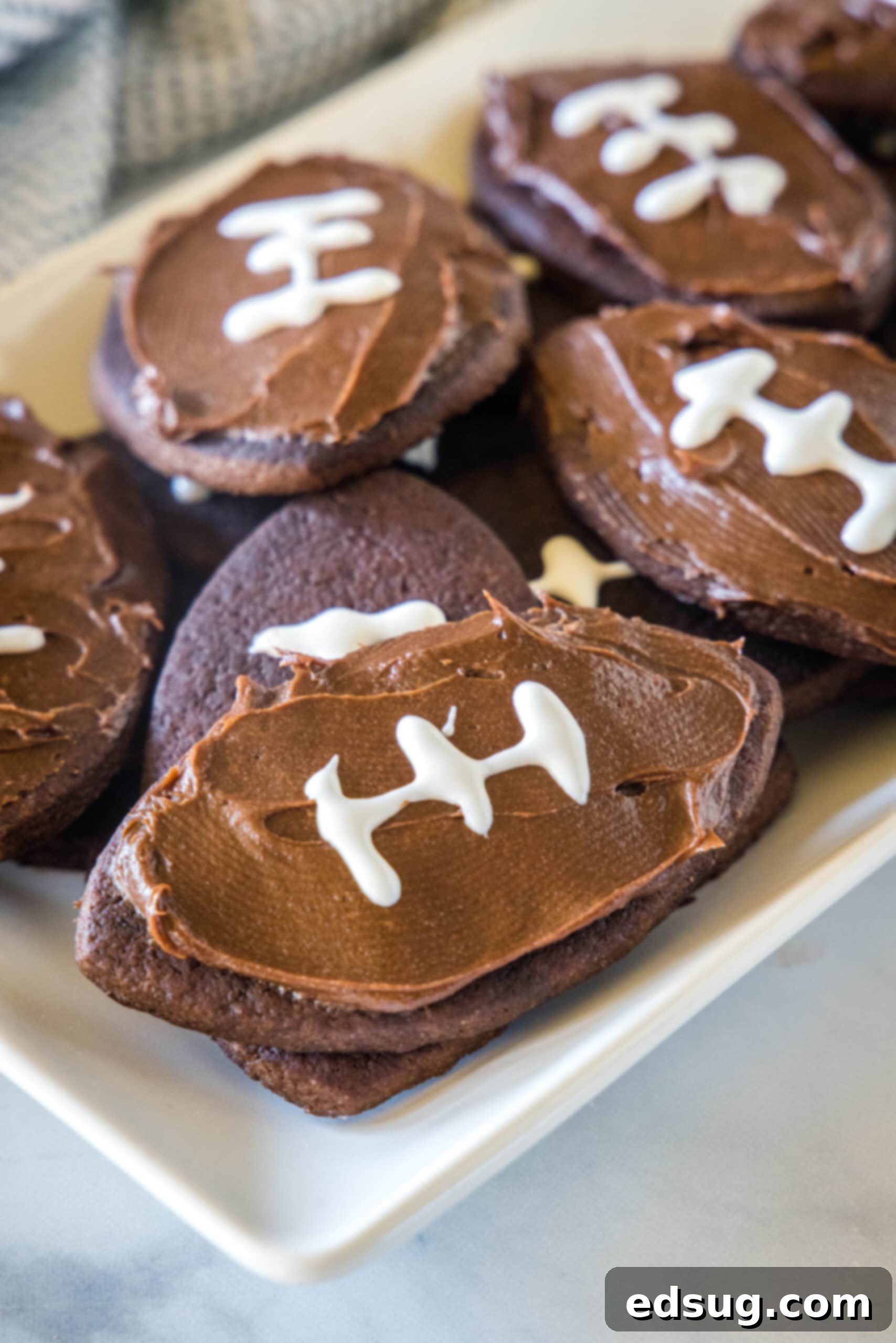Assorted frosted football cookies on a rectangular white plate, ready for game day.