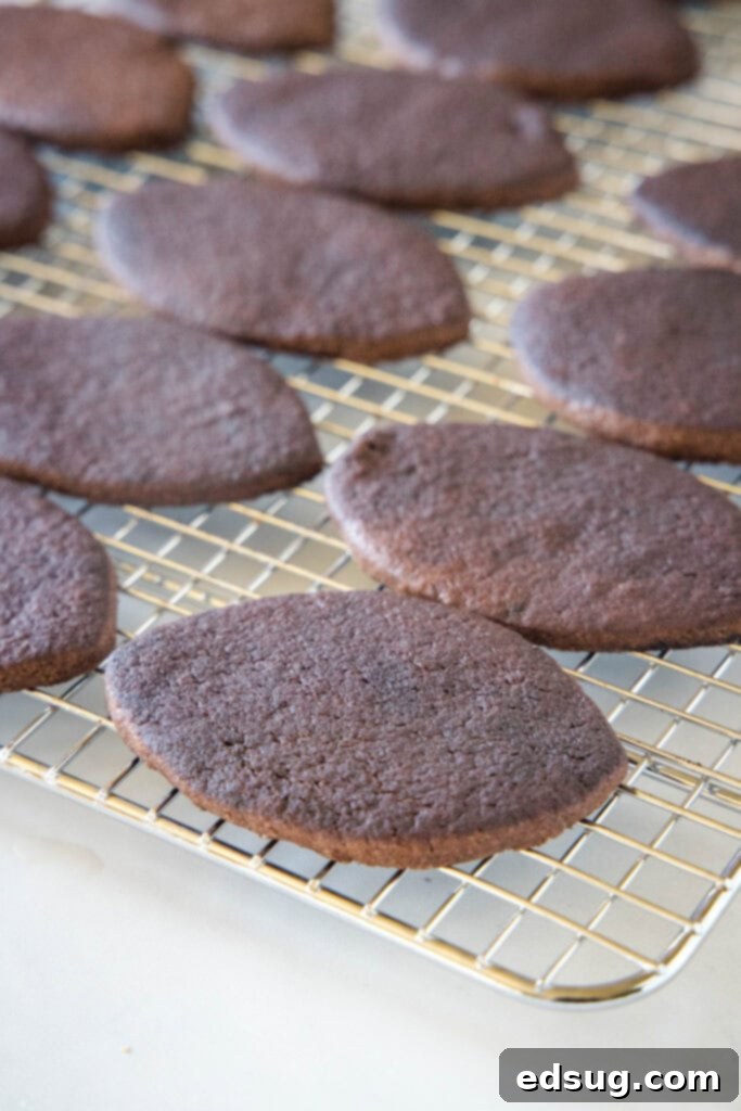 Rows of freshly baked chocolate sugar cookies, shaped like footballs, cooling on a wire rack.