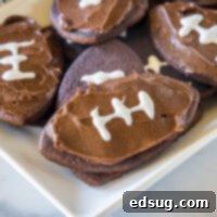 Assorted frosted football cookies on a rectangular white plate.