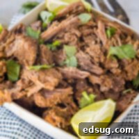 Tender Mexican Shredded Beef 2 Mexican shredded beef in a square bowl garnished with cilantro and a lime wedge.