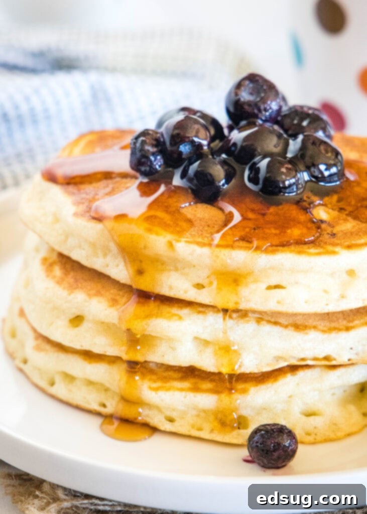 Syrup pouring over a tall stack of golden Greek yogurt pancakes