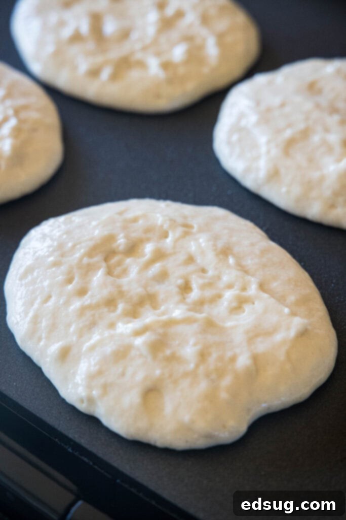 Greek yogurt pancakes cooking on a griddle