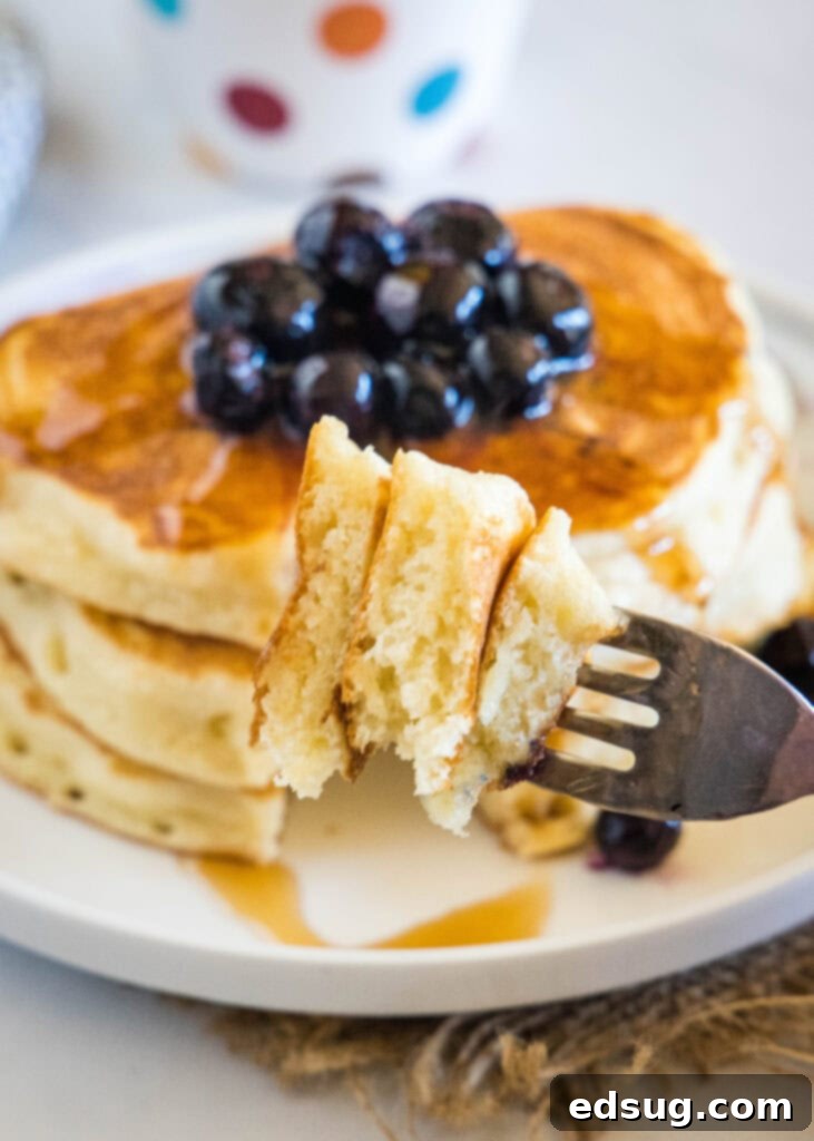 A fork taking a bite of a Greek yogurt pancake topped with fruit