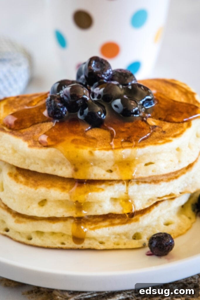 A stack of Greek yogurt pancakes with blueberries and syrup in the background