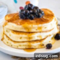 cropped close up of stack of pancakes with syrup and blueberries
