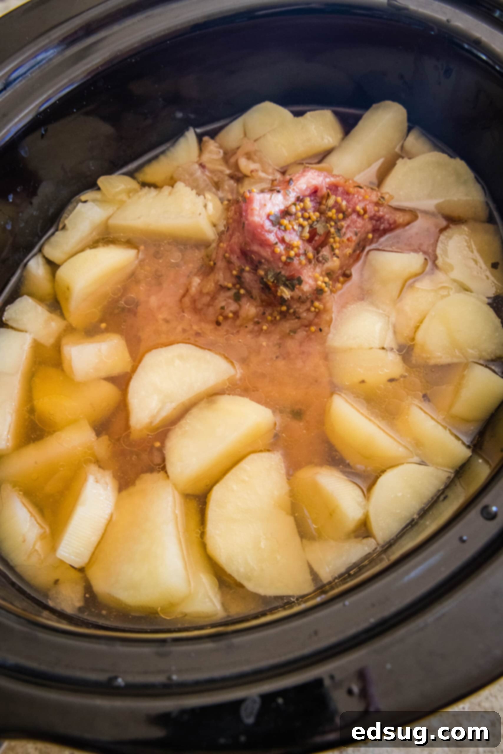 Cooked corned beef, tender onions, and perfectly cooked potatoes inside the slow cooker, ready to be served.