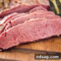 Perfectly sliced slow cooker corned beef on a wooden cutting board, ready for serving.