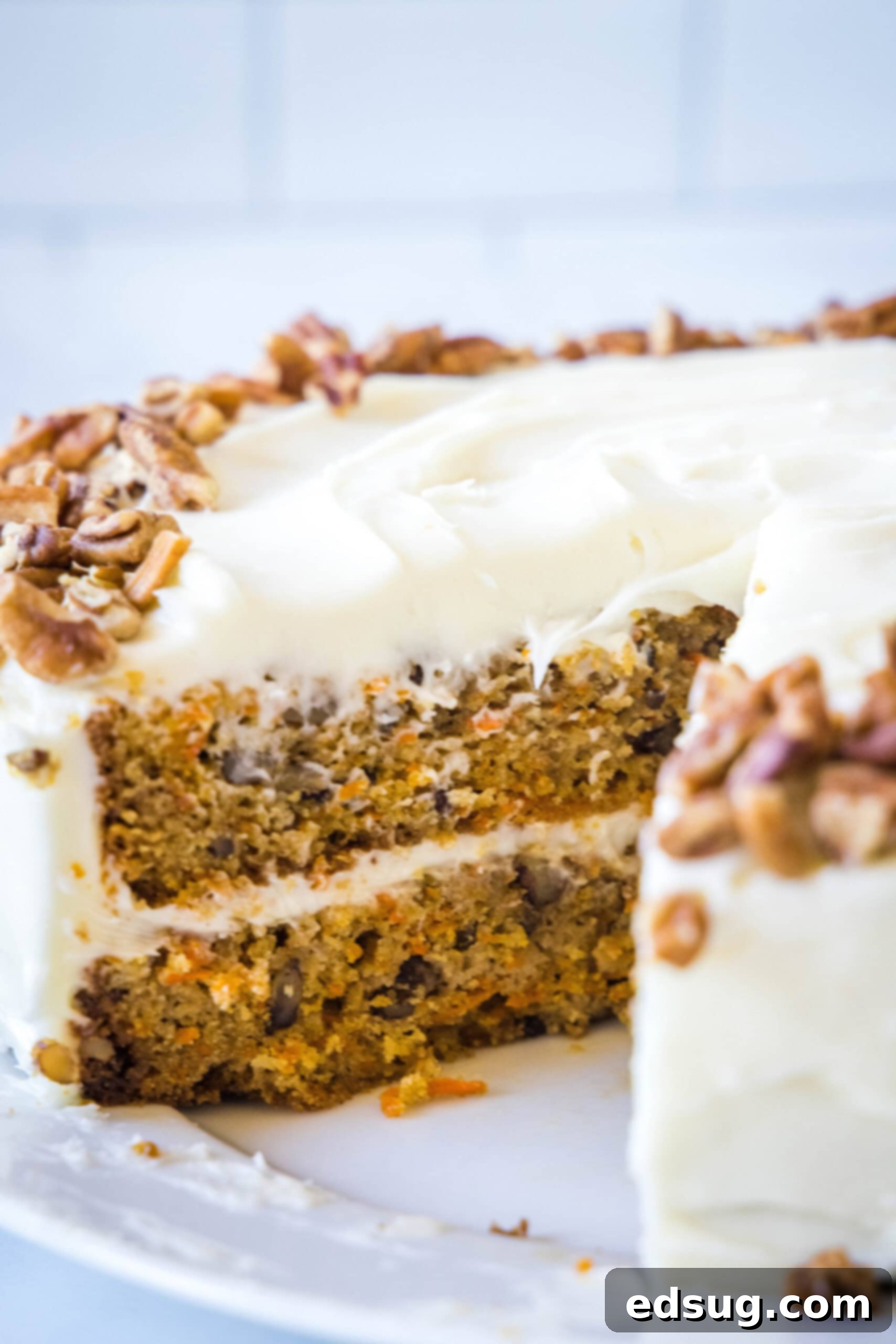 The best homemade carrot cake! Made from moist cake layers loaded with crunchy pecans, filled and frosted with sweet cream cheese frosting. Frosted carrot cake with a slice missing.
