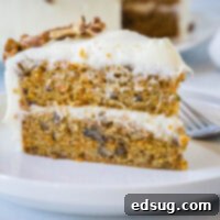 Decadent Carrot Cake 2 A slice of frosted carrot cake on a white plate next to a fork.