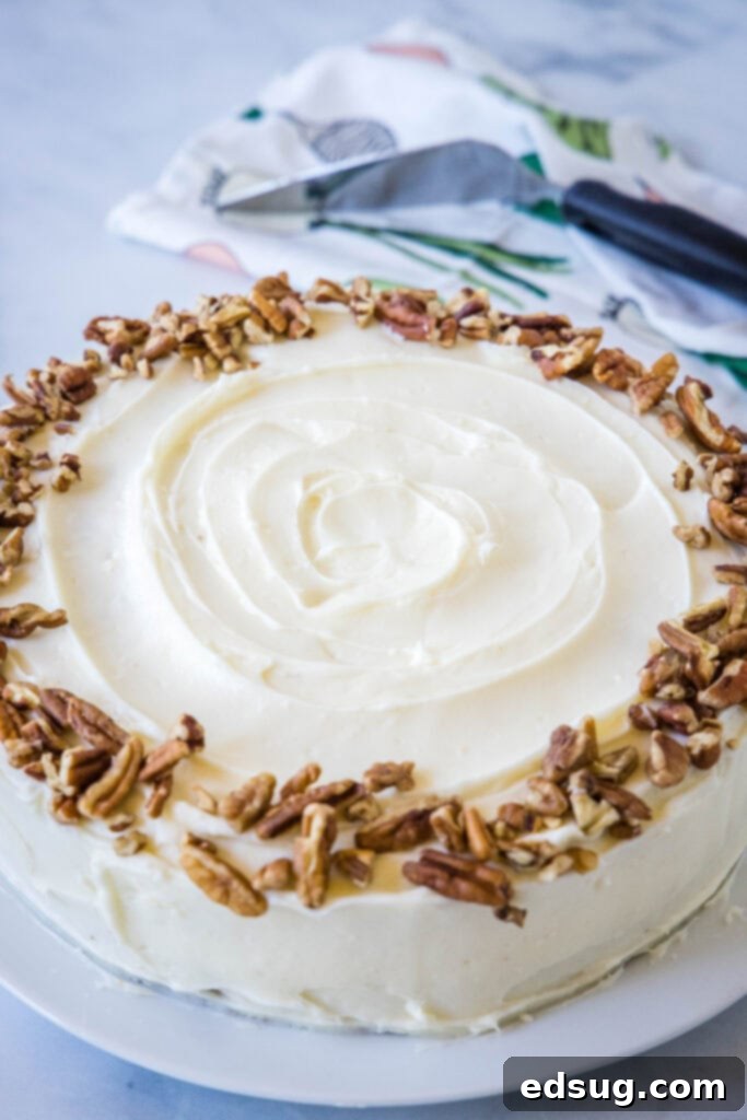 The best homemade carrot cake! Made from moist cake layers loaded with crunchy pecans, filled and frosted with sweet cream cheese frosting. A whole carrot cake frosted with cream cheese frosting and garnished with chopped pecans.