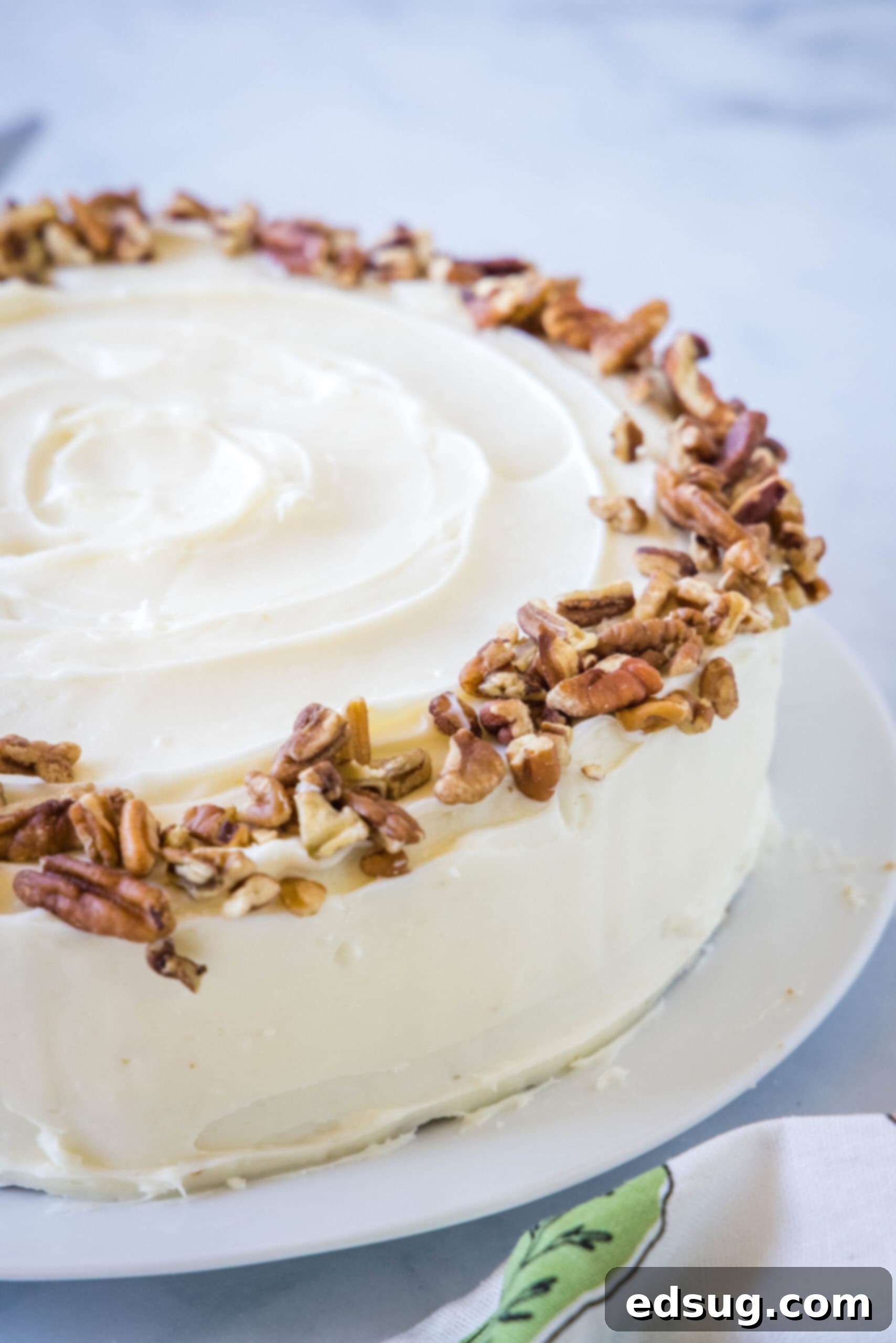 The best homemade carrot cake! Made from moist cake layers loaded with crunchy pecans, filled and frosted with sweet cream cheese frosting. A whole carrot cake frosted with cream cheese frosting and garnished with chopped pecans.