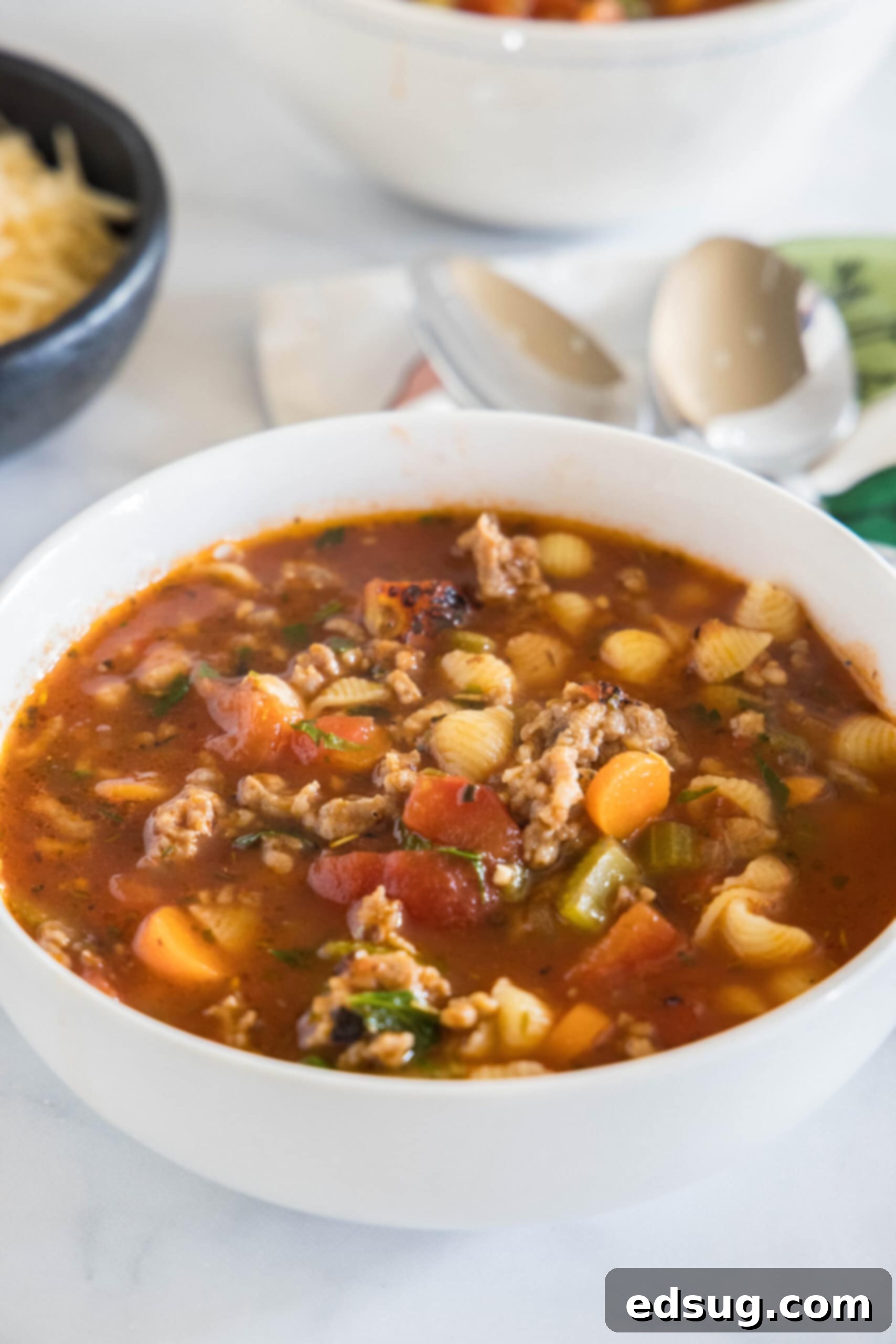 A steaming bowl of hearty Italian sausage soup, garnished with fresh parsley.