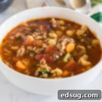 A bowl of Italian sausage soup garnished with fresh parsley.