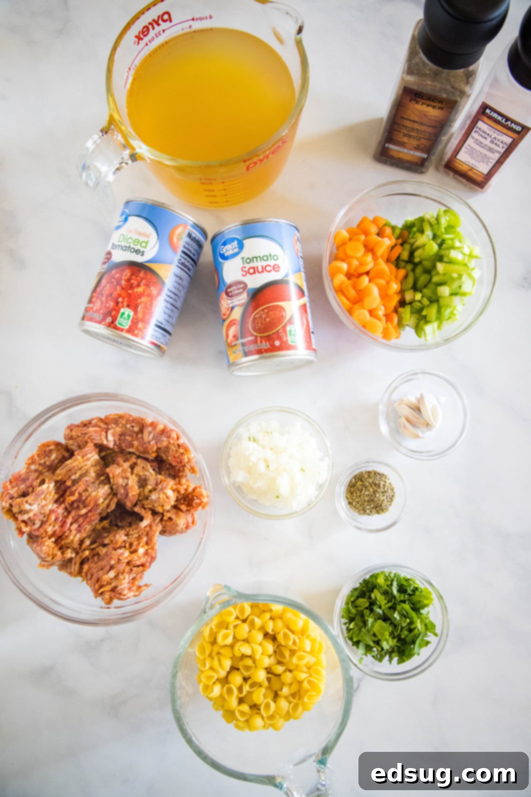 Fresh ingredients for making Italian sausage soup laid out on a wooden board.