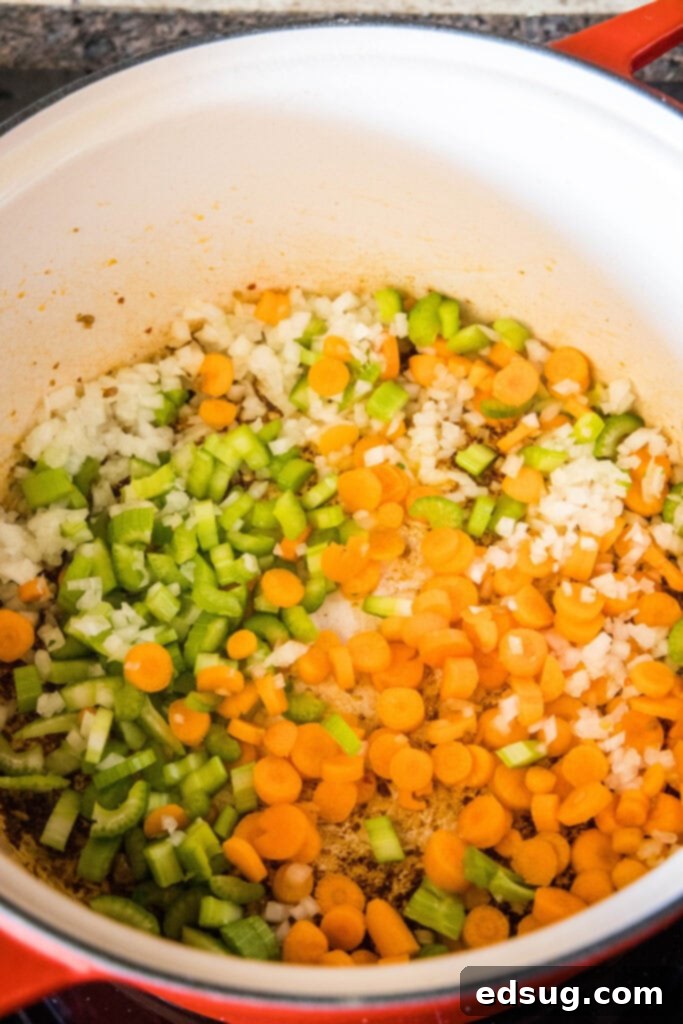 Finely diced onions, carrots, and celery being sautéed in a large pot.