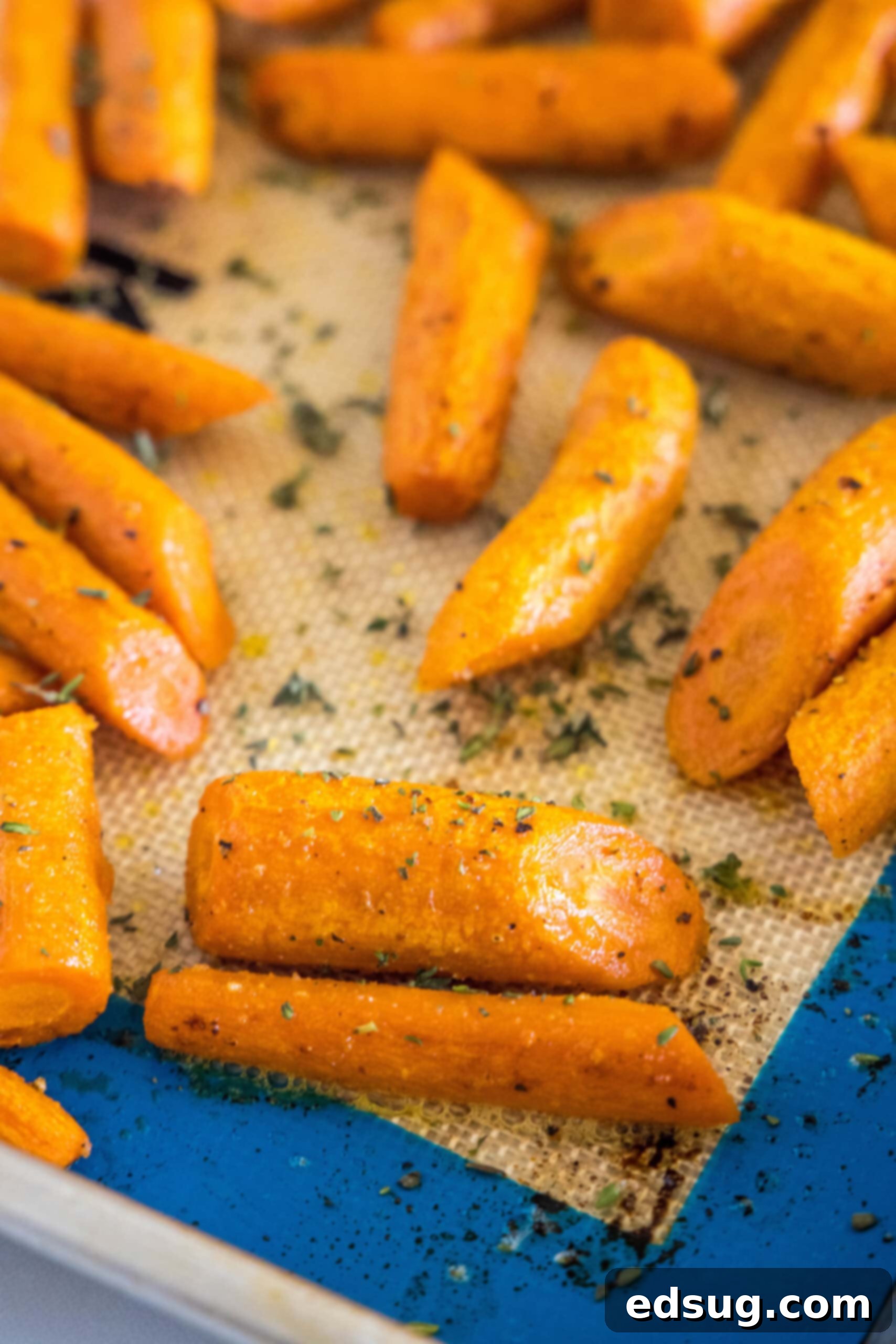 These tender oven roasted carrots come out crispy, caramelized, and full of flavor. They're the perfect easy side dish for any occasion! Seasoned roasted carrots spread out on a baking sheet, golden brown and ready to be served.