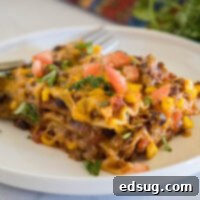 Ultimate Tex-Mex Lasagna 1 A serving of Mexican lasagna on a white plate with a fork in the background.