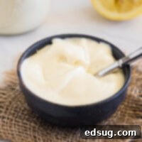Homemade mayo in a black bowl with a spoon, highlighting its creamy texture.