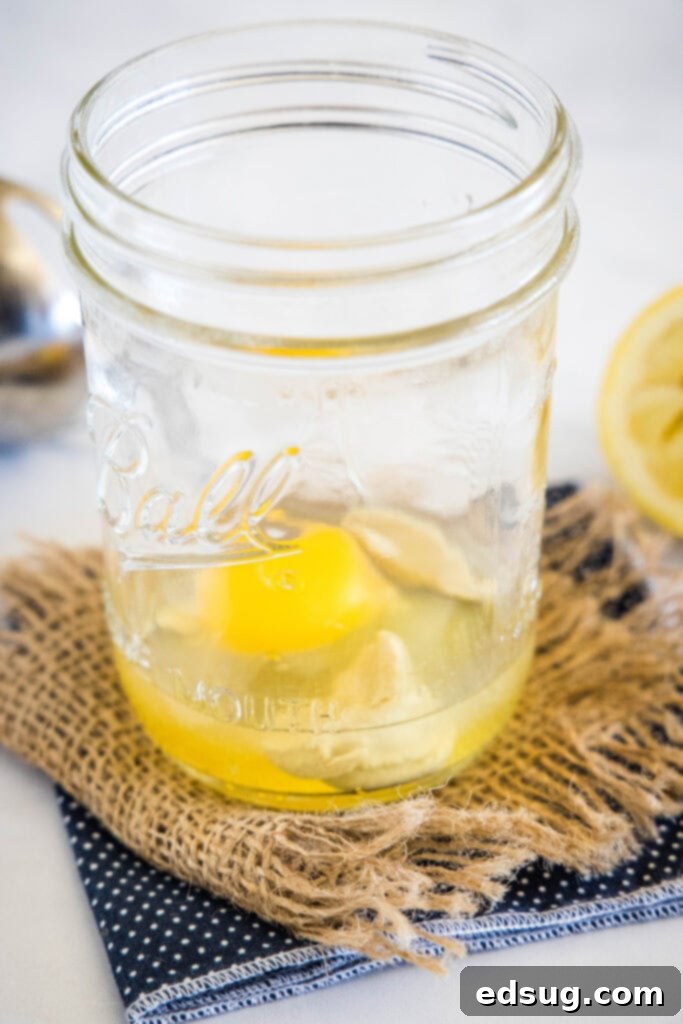 A single whole egg gently placed at the bottom of a clear glass mason jar, ready for the next ingredients of homemade mayo.