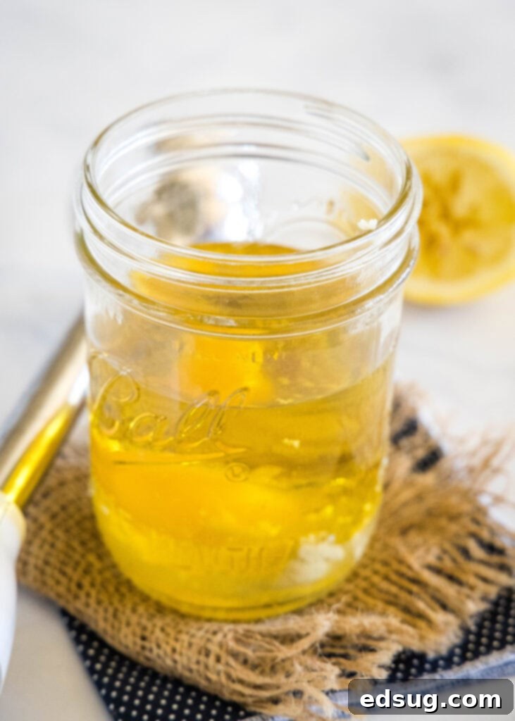 All homemade mayo ingredients, including oil and egg, combined and settled in a tall glass mason jar before blending, showcasing the distinct layers.