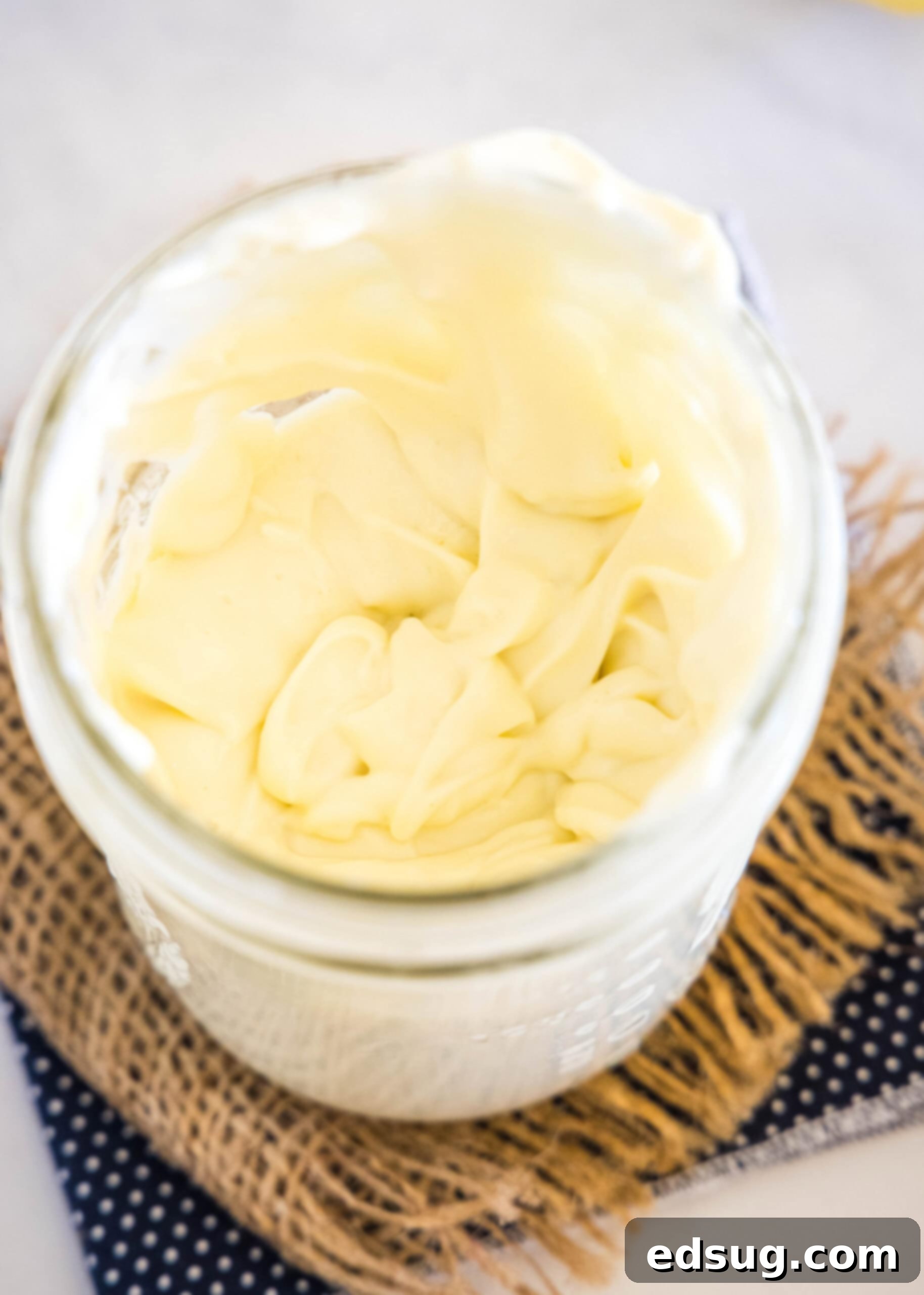 An overhead view of a jar filled with freshly made, creamy homemade mayonnaise, highlighting its smooth texture and readiness for use.