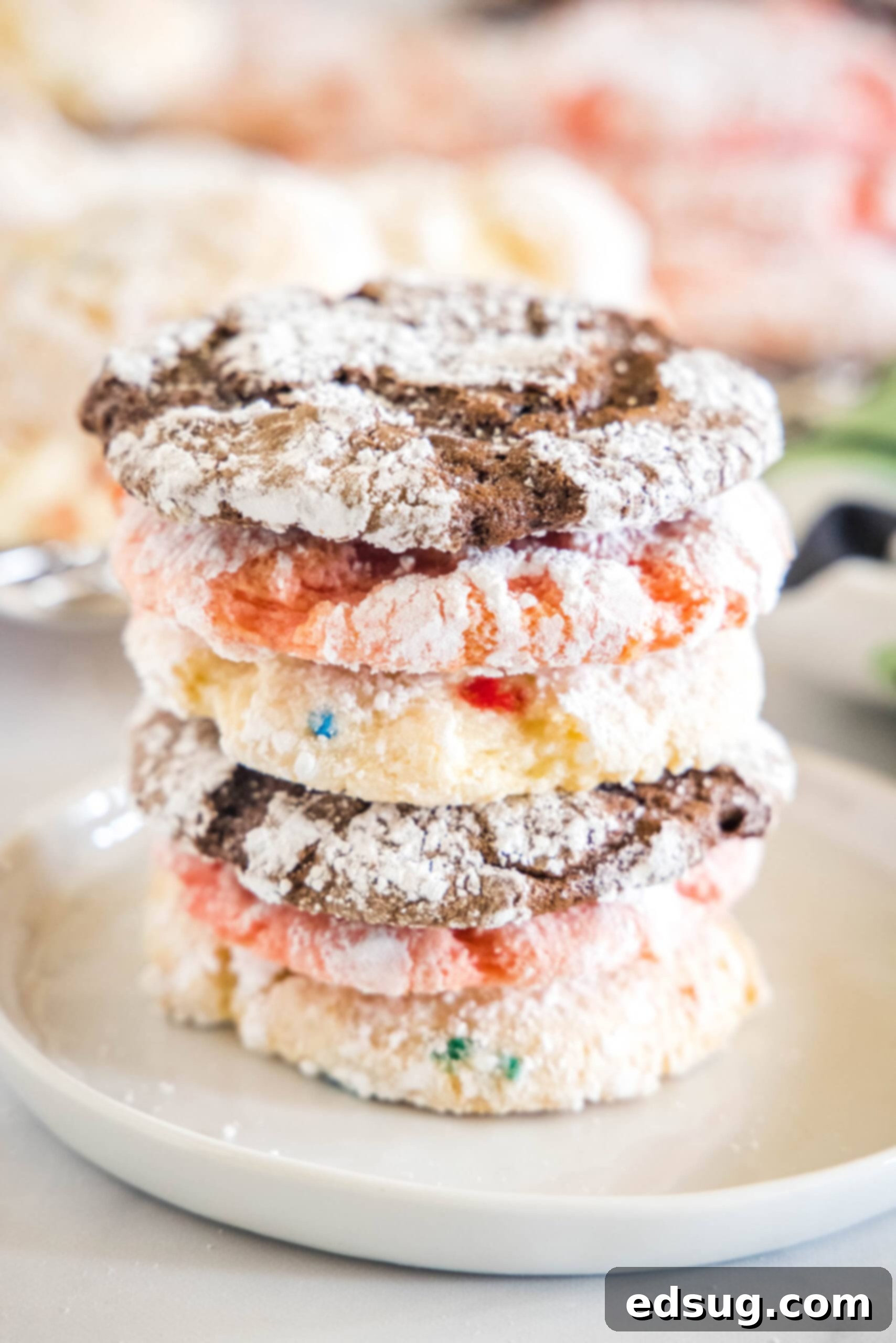 Assorted Cool Whip cookies stacked on a white plate, showcasing various flavors like strawberry, funfetti, and chocolate. These cookies are soft, sweet, and easy to make with cake mix.