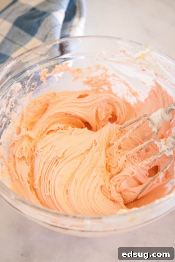 Cool Whip cookie dough being mixed in a glass bowl with a hand mixer, showing a light and fluffy consistency of the batter.