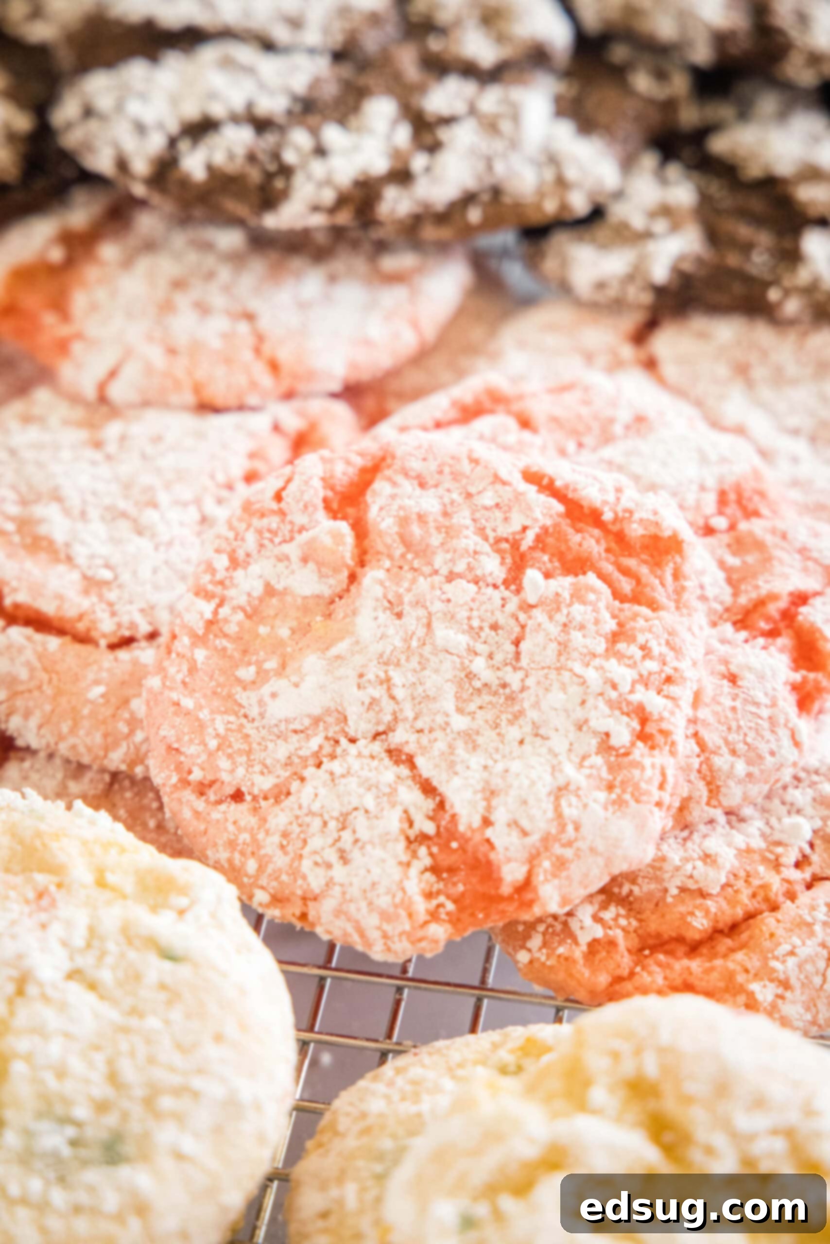 Close up view of assorted Cool Whip cookies with various crinkle patterns and flavors, like strawberry, chocolate, and funfetti, on a wire rack.