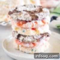 Assorted Cool Whip cookies stacked on a white plate, showcasing various cake mix flavors and crinkled powdered sugar tops, ready to be served.