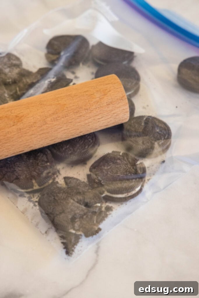 Prepare to be obsessed with Oreo fluff! Make this easy no-bake dessert with 5 ingredients in 5 minutes. It's perfect for dipping! Oreos in a zip-top bag being crushed with a wooden rolling pin.