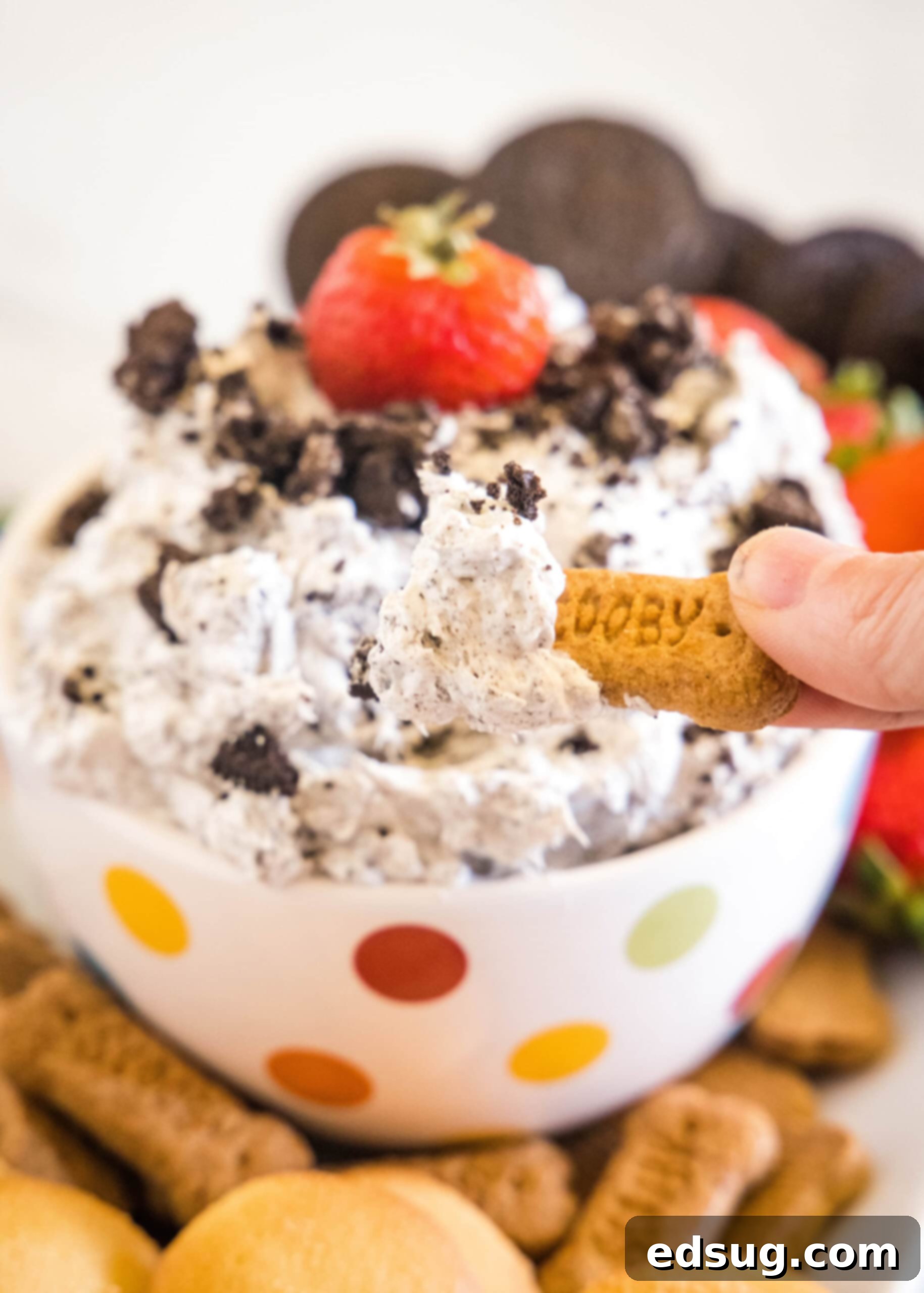 Prepare to be obsessed with Oreo fluff! Make this easy no-bake dessert with 5 ingredients in 5 minutes. It's perfect for dipping! A hand dipping a cookie into a bowl of Oreo fluff.