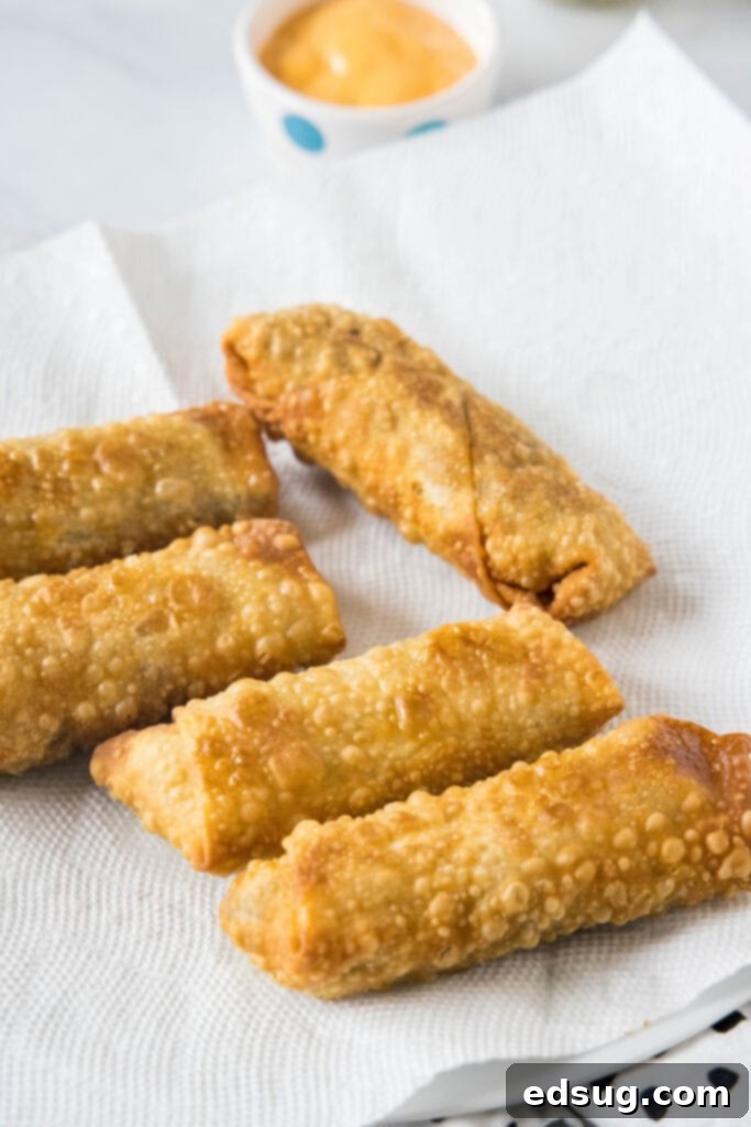 Looking for a fun and easy appetizer recipe? Try these cheeseburger egg rolls complete with creamy, tangy homemade burger sauce for dipping! Deep fried cheeseburger egg rolls on a sheet of paper towel.